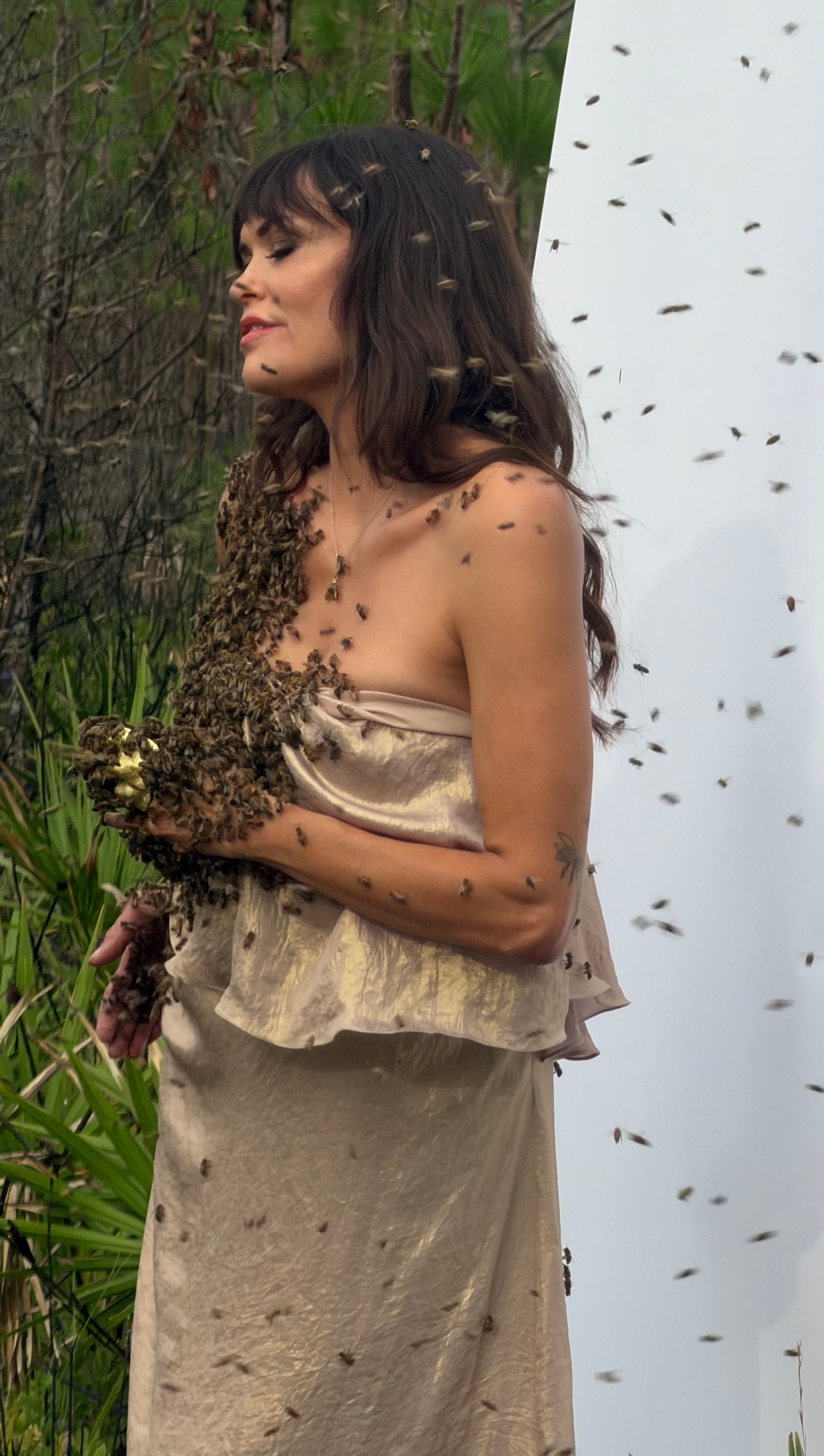 Carrie Diaz wearing a golden, vintage gown covered in live bees.