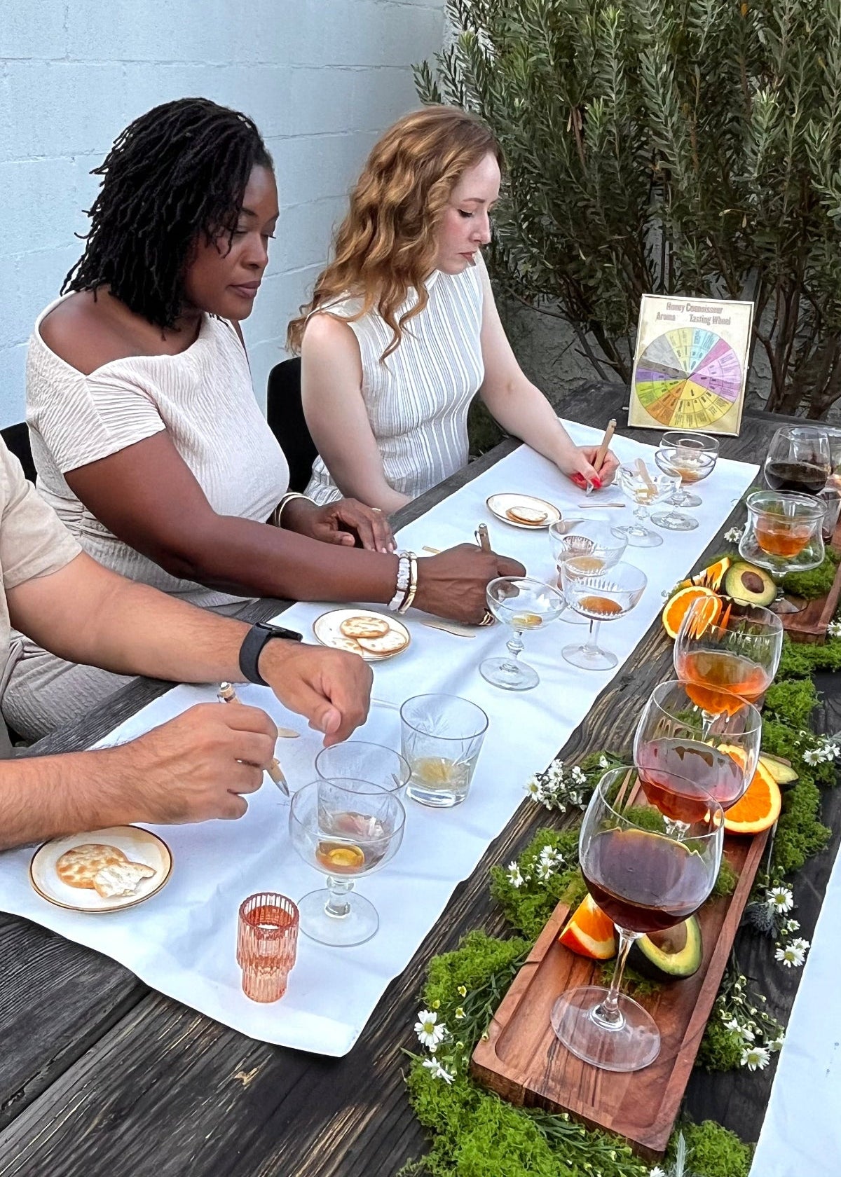 Guests enjoying a guided honey-tasting experience in Los Angeles, California. The formal table is beautifully decorated with a variety of exotic honeys in crystal goblets and wine glasses.